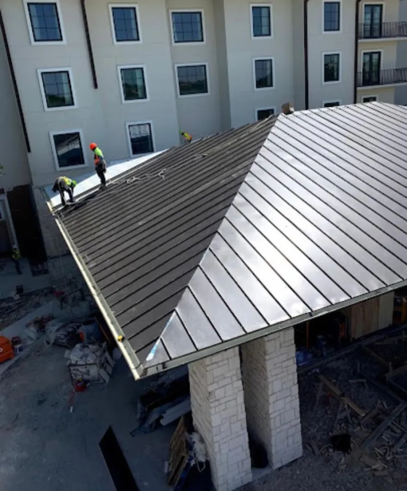 Crew installing standing seam metal roof panels on a commercial project in Lewistown